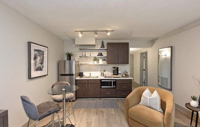 A modern kitchen with a glass table and a brown armchair.