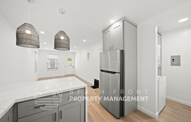 a white kitchen with grey cabinets and a stainless steel refrigerator