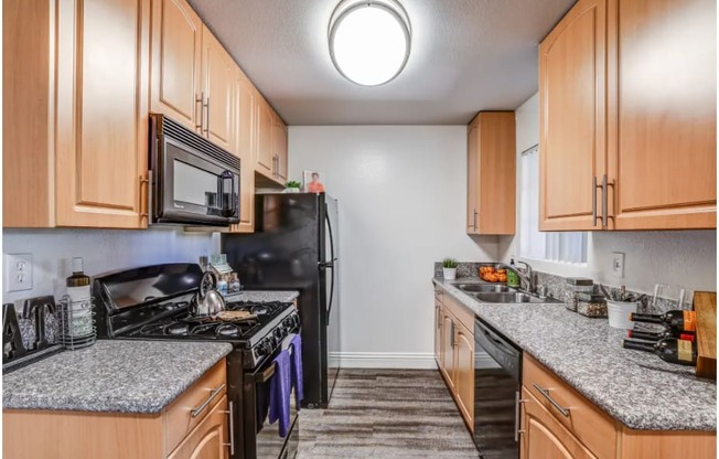 a kitchen with wood cabinets and granite counter tops and black appliances