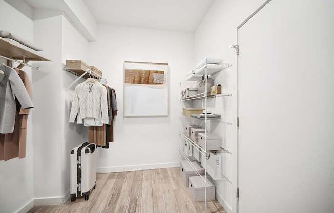 A walk in closet with clothes and a suitcase.