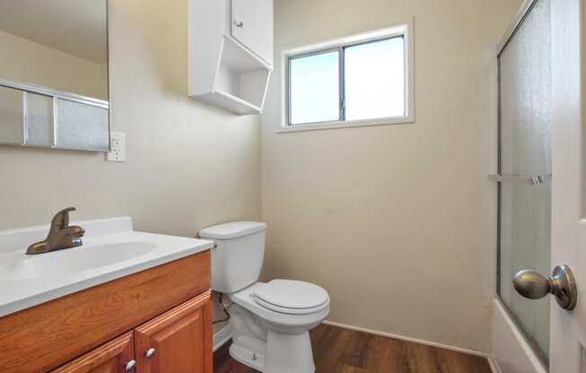 Bathroom with shower and tub combo at the right, single vanity with wood style cabinet