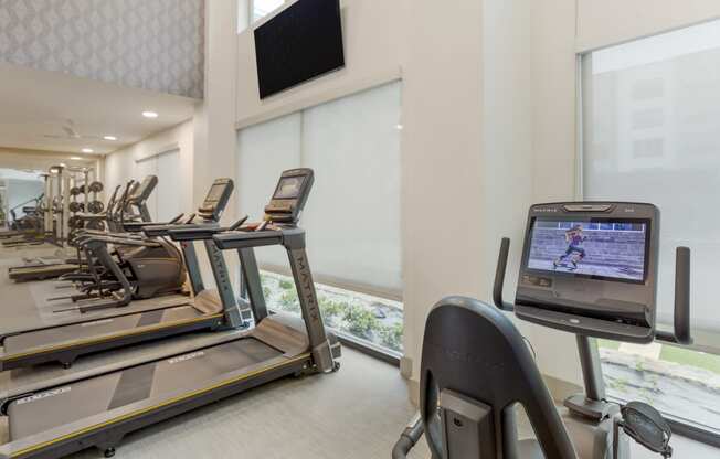 a room filled with cardio equipment and a flat screen tv