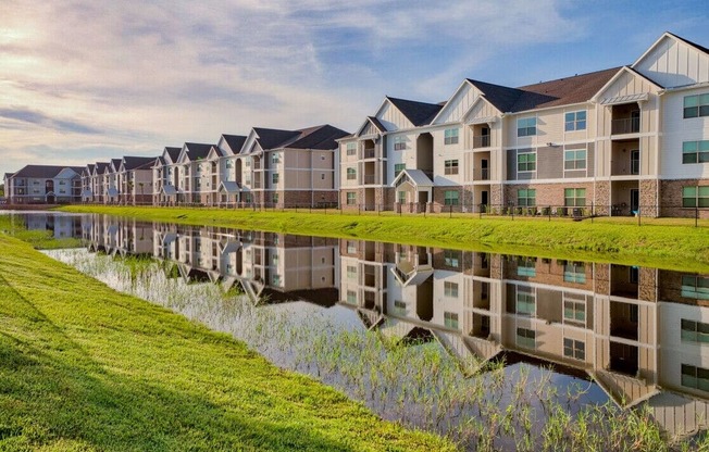 an apartment building is reflected in a retention pond