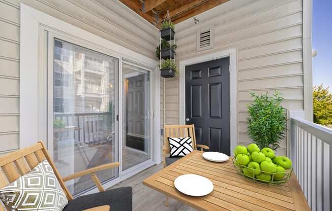 a patio with a wooden table and chairs and a black door at MetroPlace at Town Center, Camp Springs, 20746