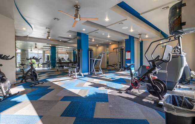 a gym with treadmills and other exercise equipment in a building with blue pillars