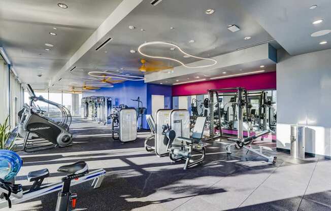 A gym with a variety of equipment including treadmills, stationary bikes, and weight machines.