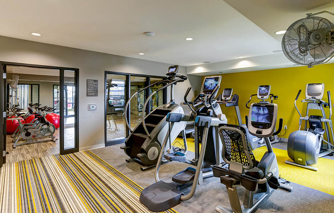 a gym with cardio equipment and weights in a building with yellow walls