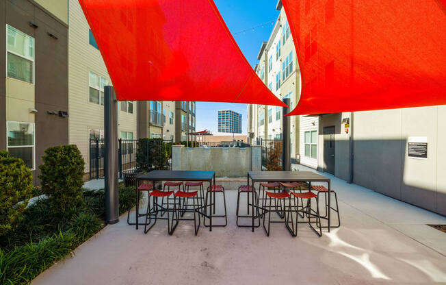 a patio with tables and chairs under large red umbrellas at Mockingbird Flats, Dallas, TX, 75206