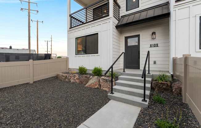 A modern house with a black front door and a gravel driveway.