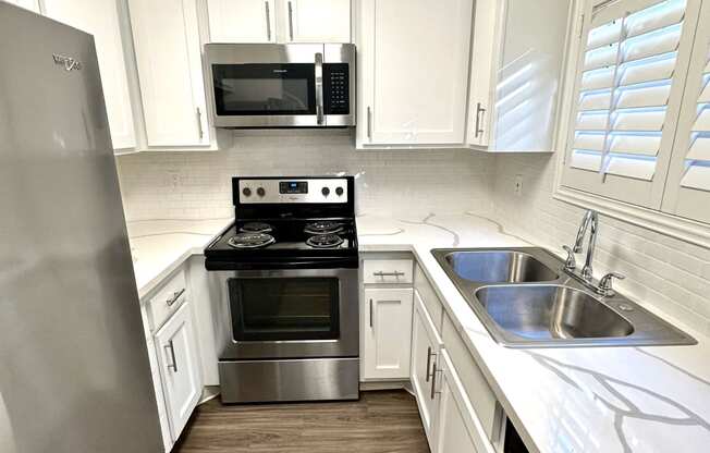 a small kitchen with white cabinets and stainless steel appliances