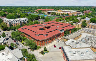 A large red building with a red roof is surrounded by trees and other buildings.