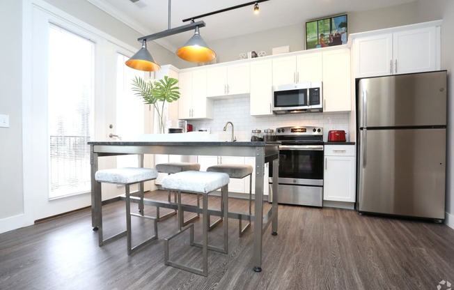 a kitchen with stainless steel appliances and a bar with three stools at Century Baxter Avenue, Louisville, 40204