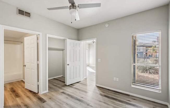 A room with a ceiling fan and a window with blinds.