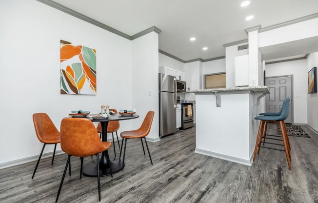 a dining area with a table and chairs and a kitchen with a refrigerator