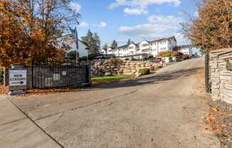 the front driveway of a house with a stone fence and a sign that reads new