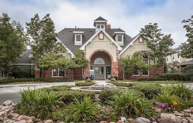 the front of a house with a fountain and gardens