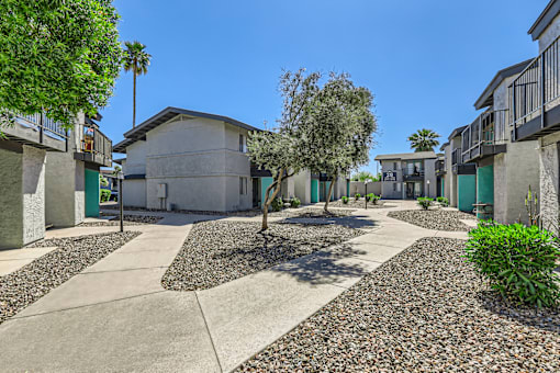 a courtyard between two buildings with trees and a blue sky