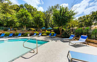 A pool with lounge chairs and pool house at Laurel Oaks in Raleigh, NC.