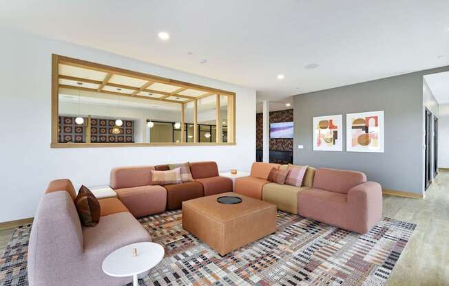 A living room with a pink couch, a white table, and a large mirror on the wall.