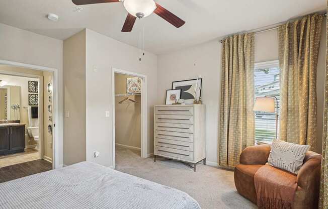 A bedroom with a bed, chair, and a ceiling fan.