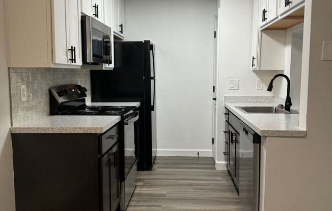 a kitchen with black appliances and white cabinets