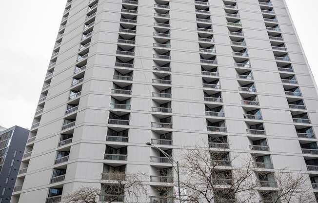 A tall building with a grey facade and balconies on the upper floors.
