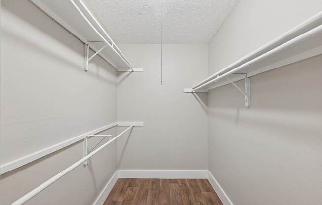 A white closet with shelves and a wooden floor.