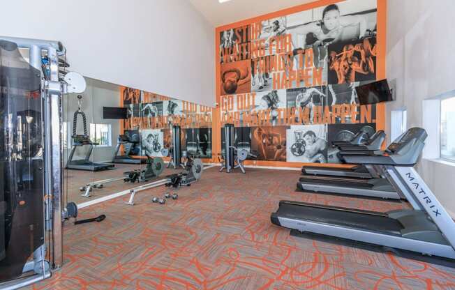 a gym with cardio equipment and a large mural on the wall