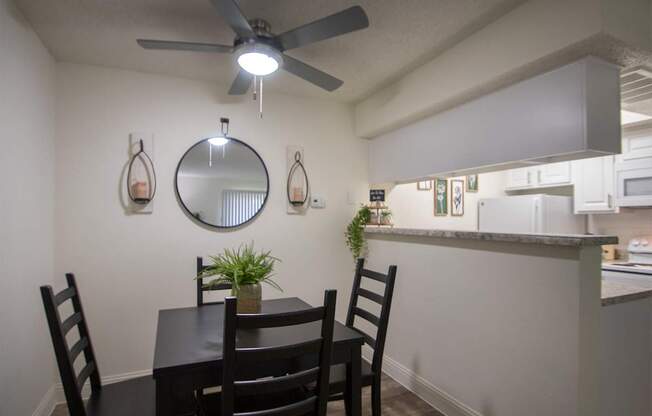 A dining room with a table and chairs in a 515 square foot 1 bedroom, 1 bath apartment home at Canyon Creek Apartments in Dallas Midtown neighborhood of Dallas, TX.