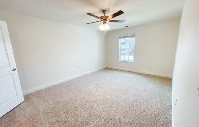 an empty living room with a ceiling fan and a window