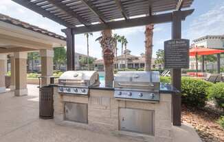 an outdoor grill area with two bbq grills under a pergola