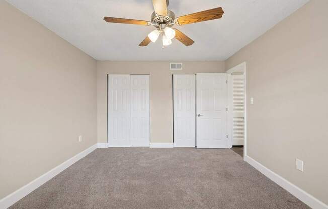 A room with a ceiling fan and carpeted floor.