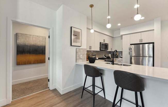A kitchen with a white counter and bar stools.