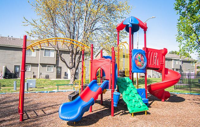 A playground with a red and blue slide and a yellow arch.