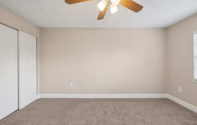 A room with a ceiling fan and carpeted floor.