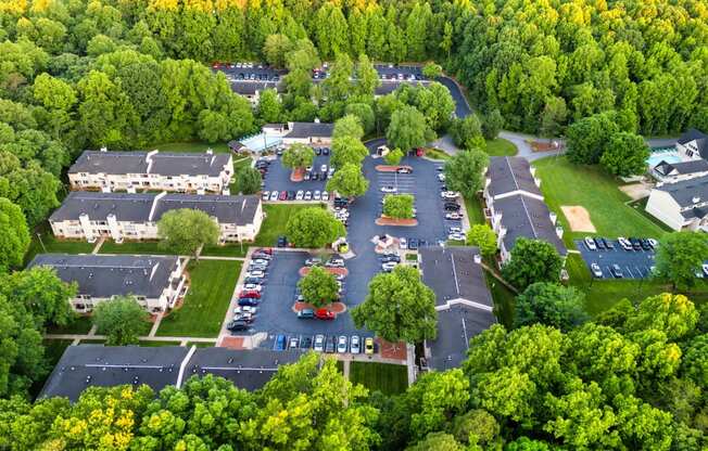 an aerial view of a parking lot with houses and trees