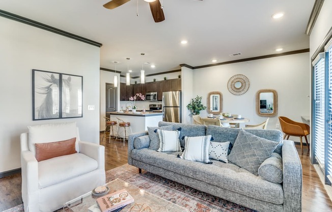 a living room with a couch and a chair in front of a kitchen