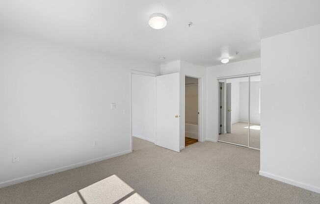 an empty room with white walls and grey carpet