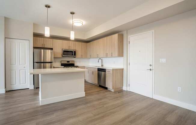 an empty kitchen with a large island and stainless steel appliances