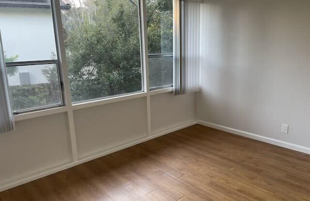 an empty room with a wood floor and large windows