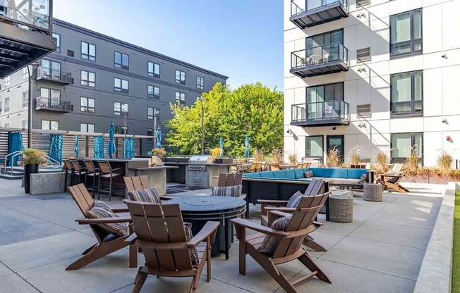 A patio with chairs and a table is surrounded by apartment buildings.