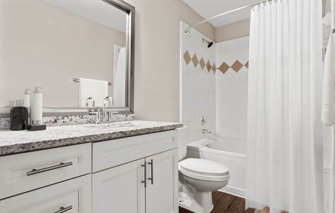 A white bathroom with a toilet, sink, and shower.