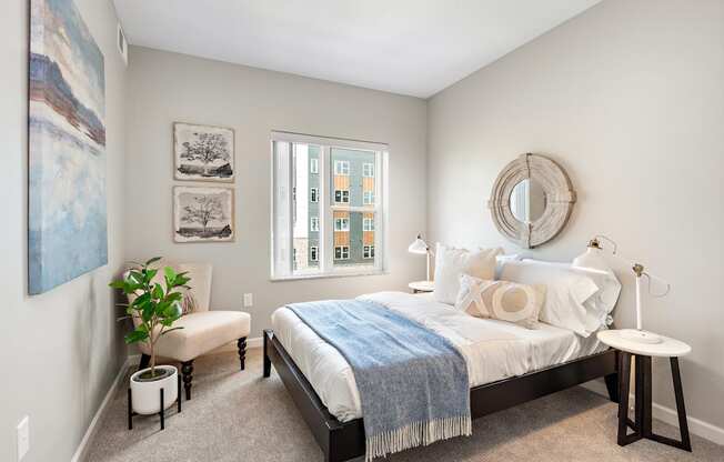 A bedroom with a bed, a bench, a side table, and a window.