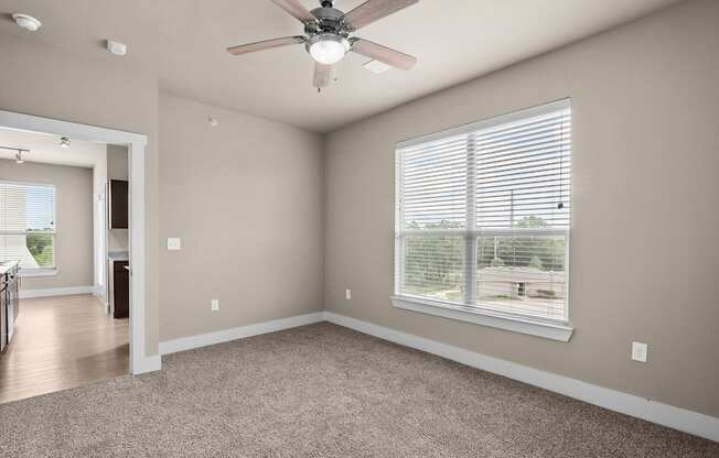 an empty living room with a ceiling fan and a large window