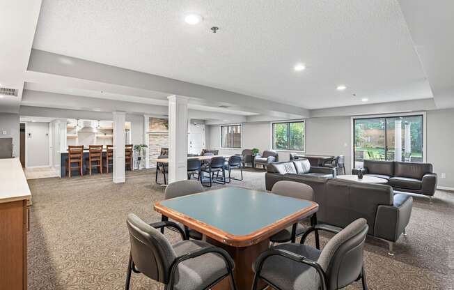 A spacious room with a table and chairs in the foreground and a kitchen area in the background.