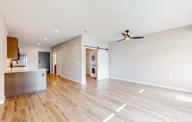 an empty living room with a kitchen and a washer and dryer