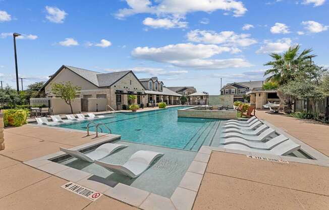 A large outdoor pool with a slide and a building in the background.