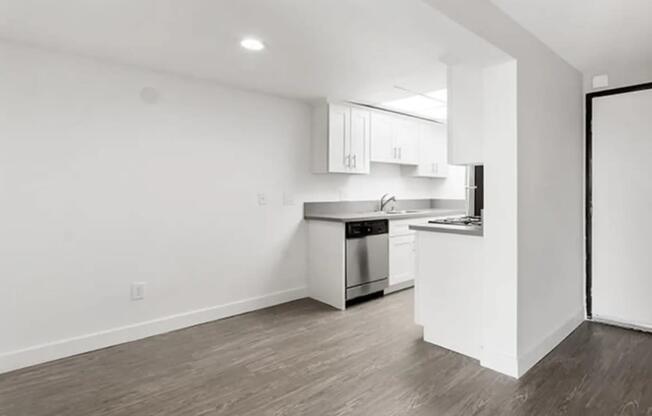 an empty living room and kitchen with white walls and wood floors