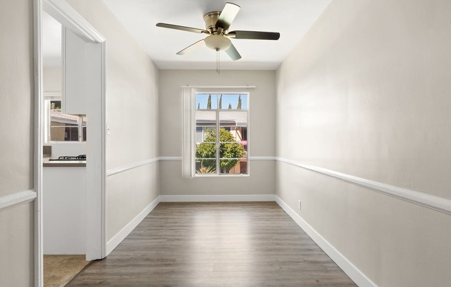 an empty room with a ceiling fan and a window