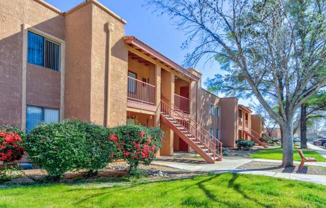a row of apartments with stairs and green grass and trees